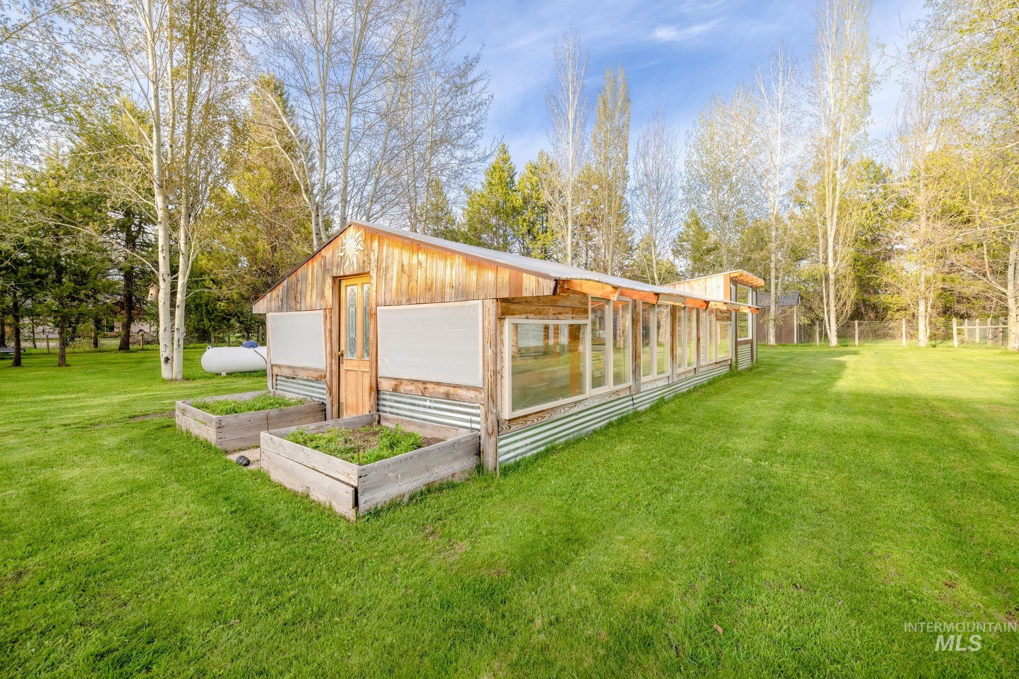 12954 Upland Road Donnelly, ID 83615 - Photo 35 of 41 Exterior space with a lawn, a garden, view of wooded area, and a garage