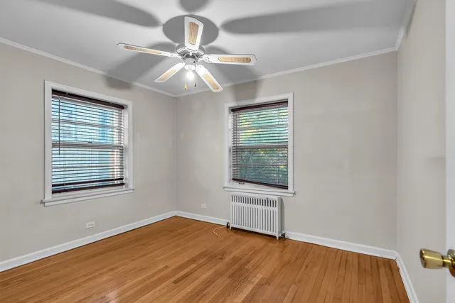 an empty room with wooden floor fan and windows