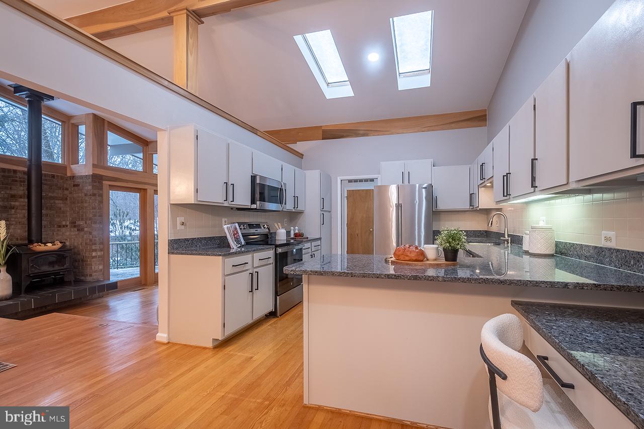 2529 Trophy Lane Reston, VA 20191 - Photo 15 of 69 a kitchen with stainless steel appliances granite countertop a stove top oven a sink a dining table and chairs with wooden floor