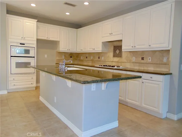 a kitchen with stainless steel appliances granite countertop a sink and white cabinets