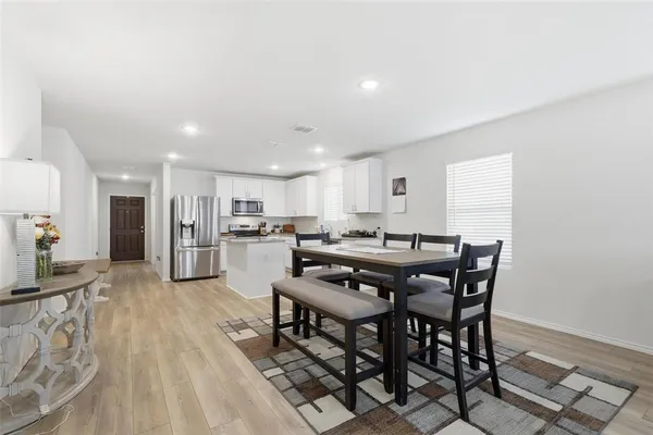 a room with stainless steel appliances kitchen island granite countertop a table chairs and a living room view