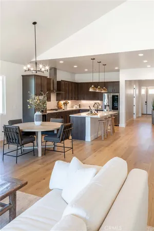 a living room with stainless steel appliances kitchen island granite countertop a table chairs and a kitchen view