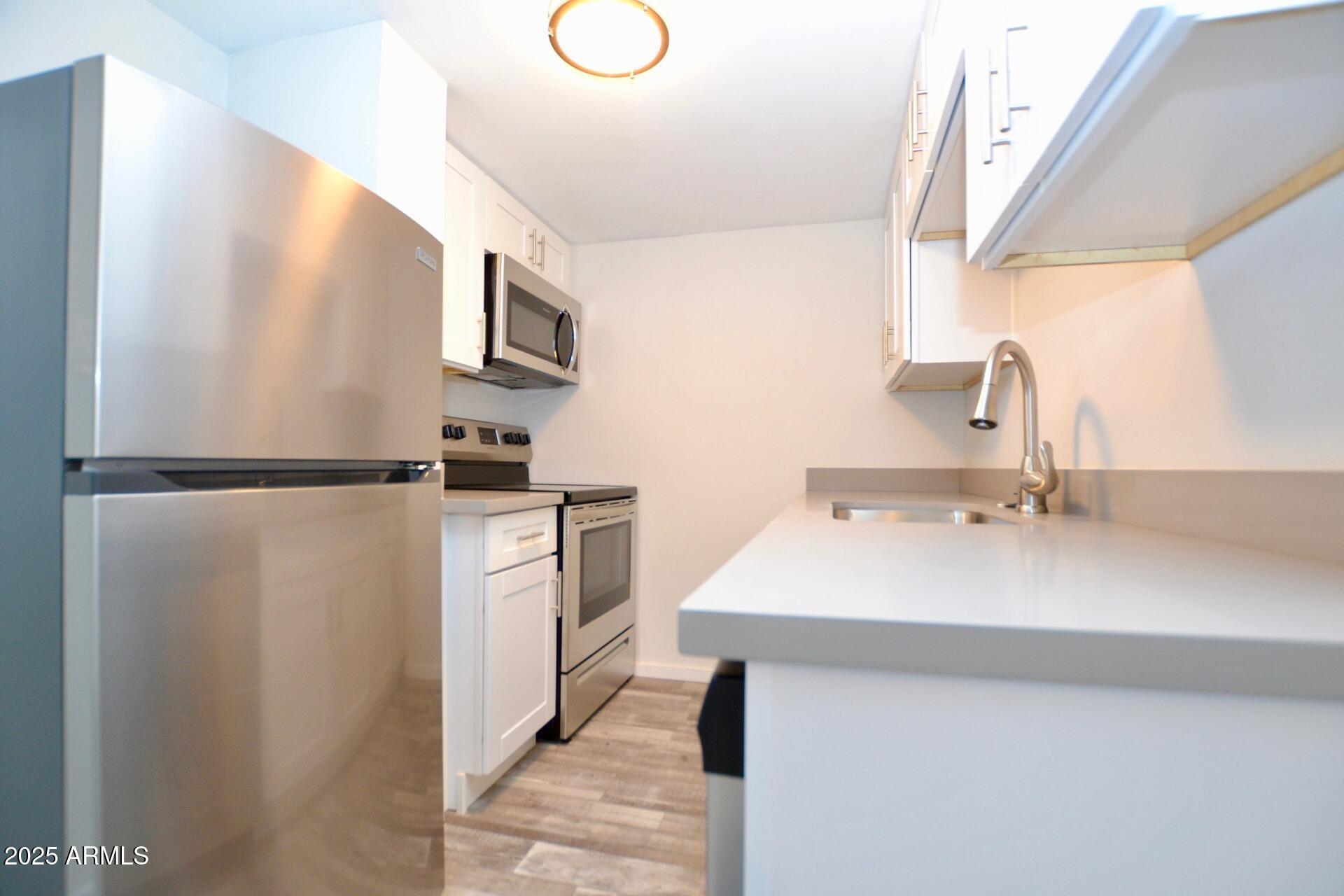 44 East Roanoke Avenue, Unit 4 Phoenix, AZ 85012 - Photo 2 of 19 a kitchen with a sink stainless steel appliances and cabinets