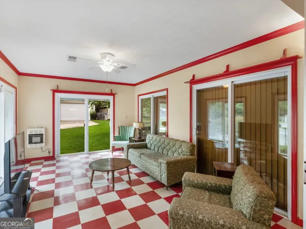 a living room with a black white checkered floor with a gaming machine and dining table