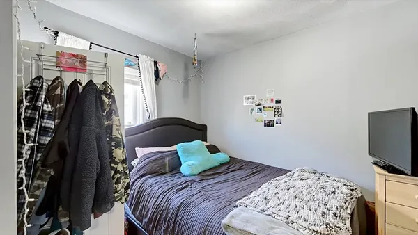 a bedroom with a bed and a flat tv screen on the dresser