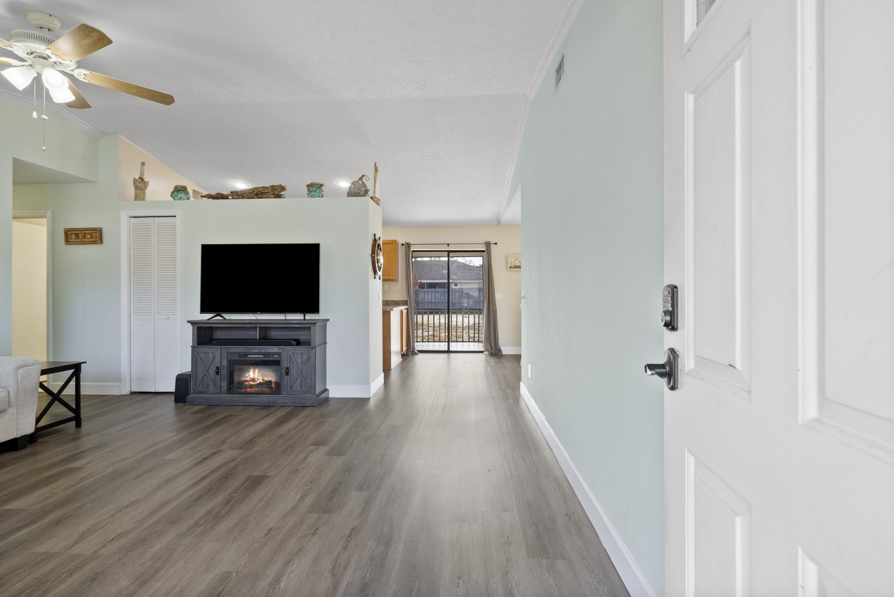 822 Southwest Harvard Road Port St. Lucie, FL 34953 - Photo 5 of 43 a view of a livingroom with a flat screen tv wooden floor and a ceiling fan