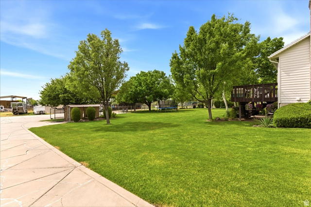 5321 South 3100th Street West Roy, UT 84067 - Photo 8 of 64 Expansive green lawn with mature trees and a private wood deck