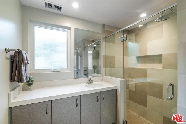 a bathroom with a double vanity sink mirror and shower