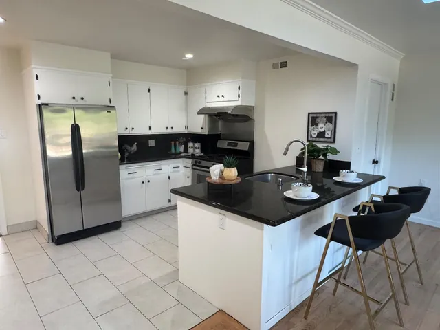 a kitchen with granite countertop a sink a stove and refrigerator