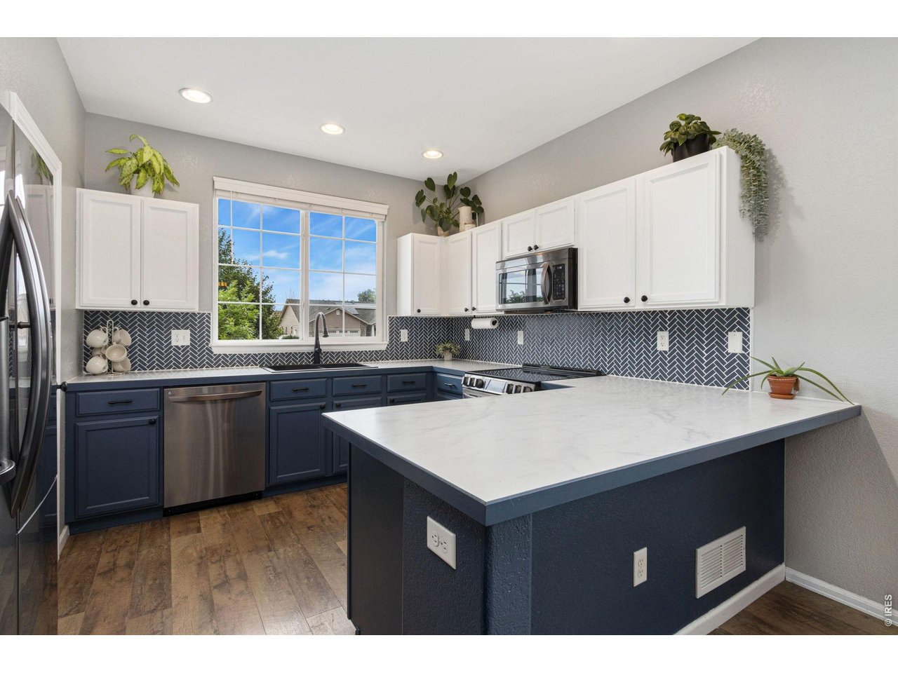 6837 McClellan Road Wellington, CO 80549 - Photo 6 of 23 Crisp white uppers, rich blue lower cabinets, and a timeless backsplash give this kitchen both style and function.