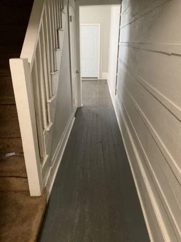a view of a hallway with wooden floor and stairs