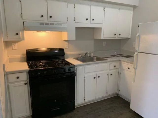 a kitchen with granite countertop white cabinets and black appliances