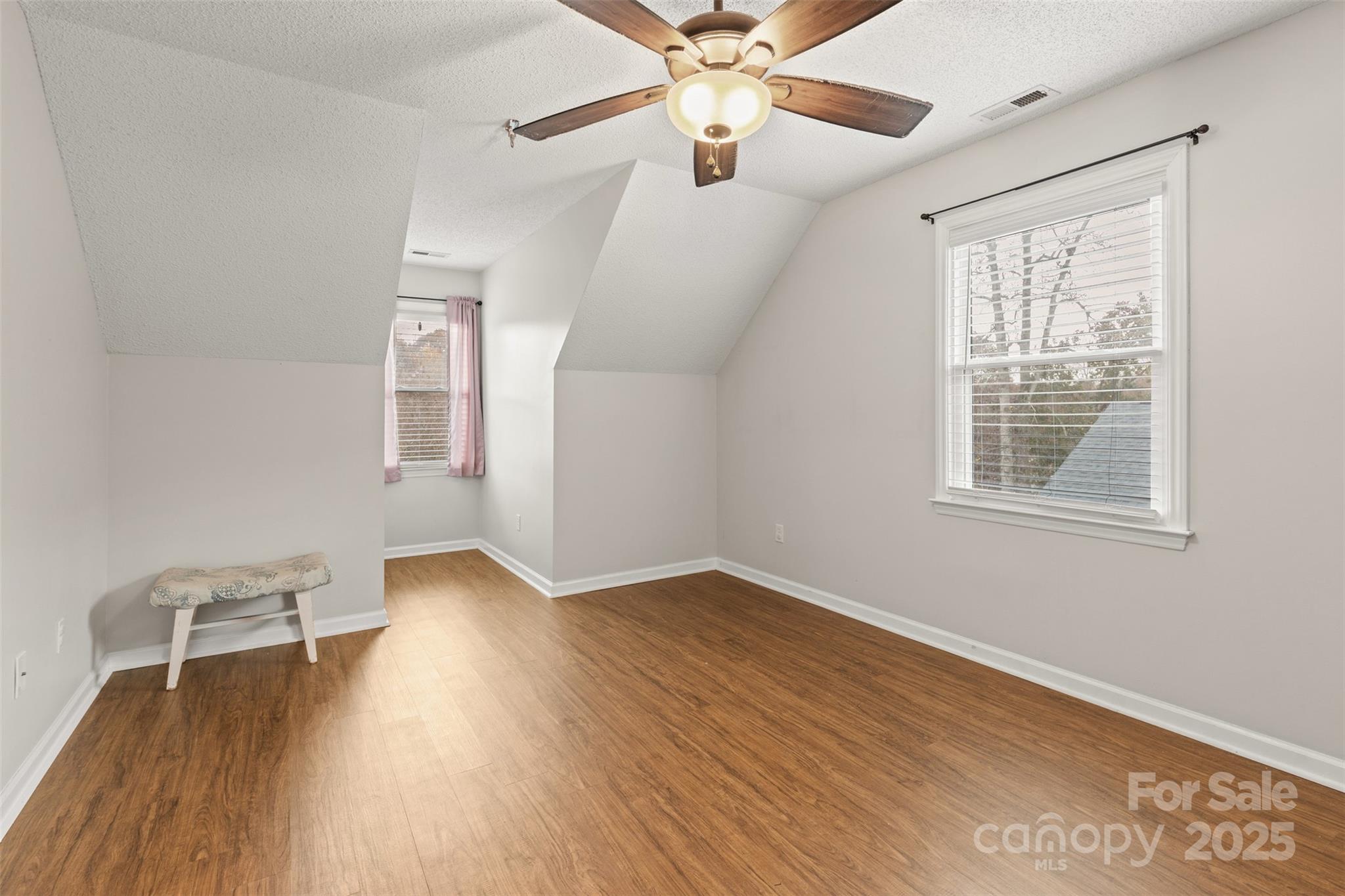 3233 6th Avenue Northeast Conover, NC 28613 - Photo 18 of 30 an empty room with wooden floor chandelier fan and windows