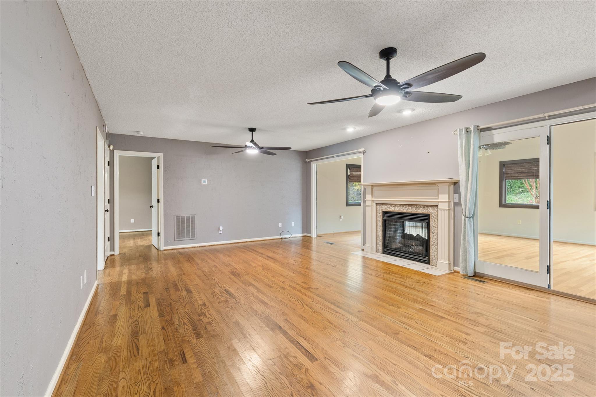 3233 6th Avenue Northeast Conover, NC 28613 - Photo 10 of 30 an empty room with wooden floor fireplace and windows