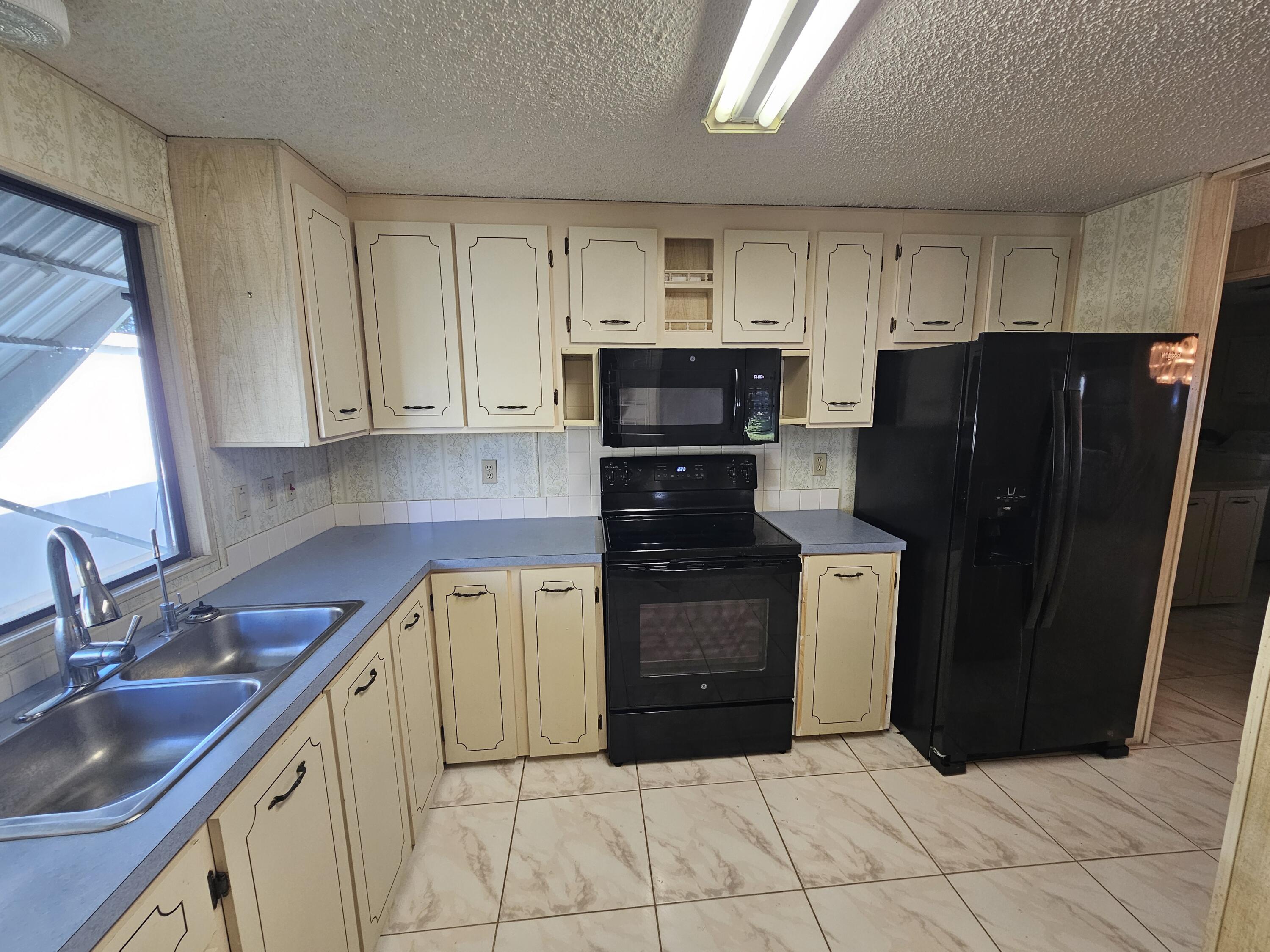 6978 Southeast Delegate Street Hobe Sound, FL 33455 - Photo 11 of 24 a kitchen with a refrigerator and a sink