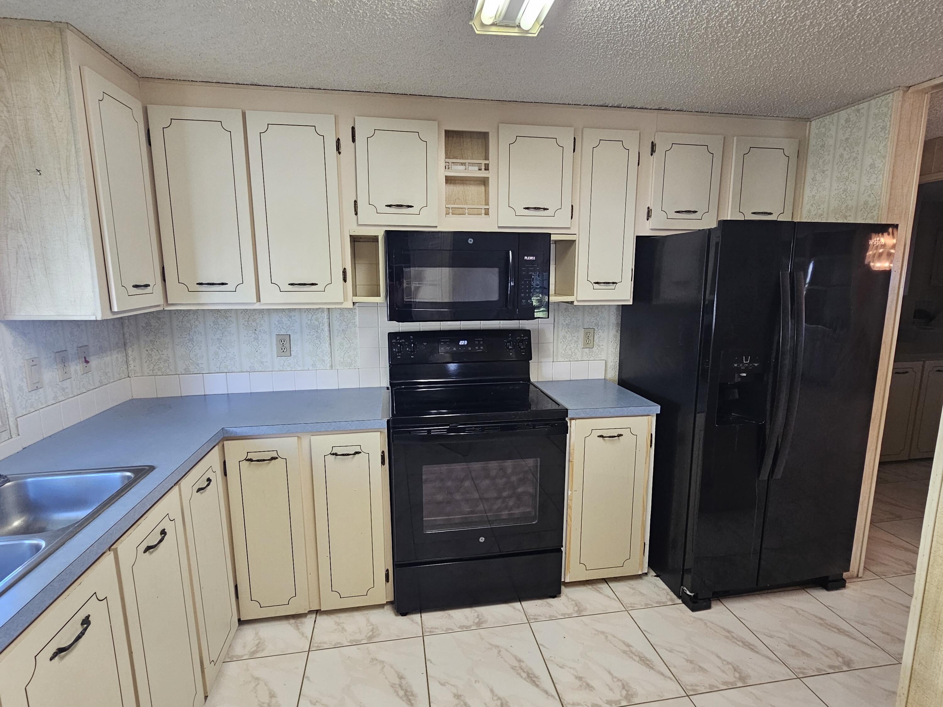 6978 Southeast Delegate Street Hobe Sound, FL 33455 - Photo 12 of 24 a kitchen with stainless steel appliances granite countertop a refrigerator and a stove