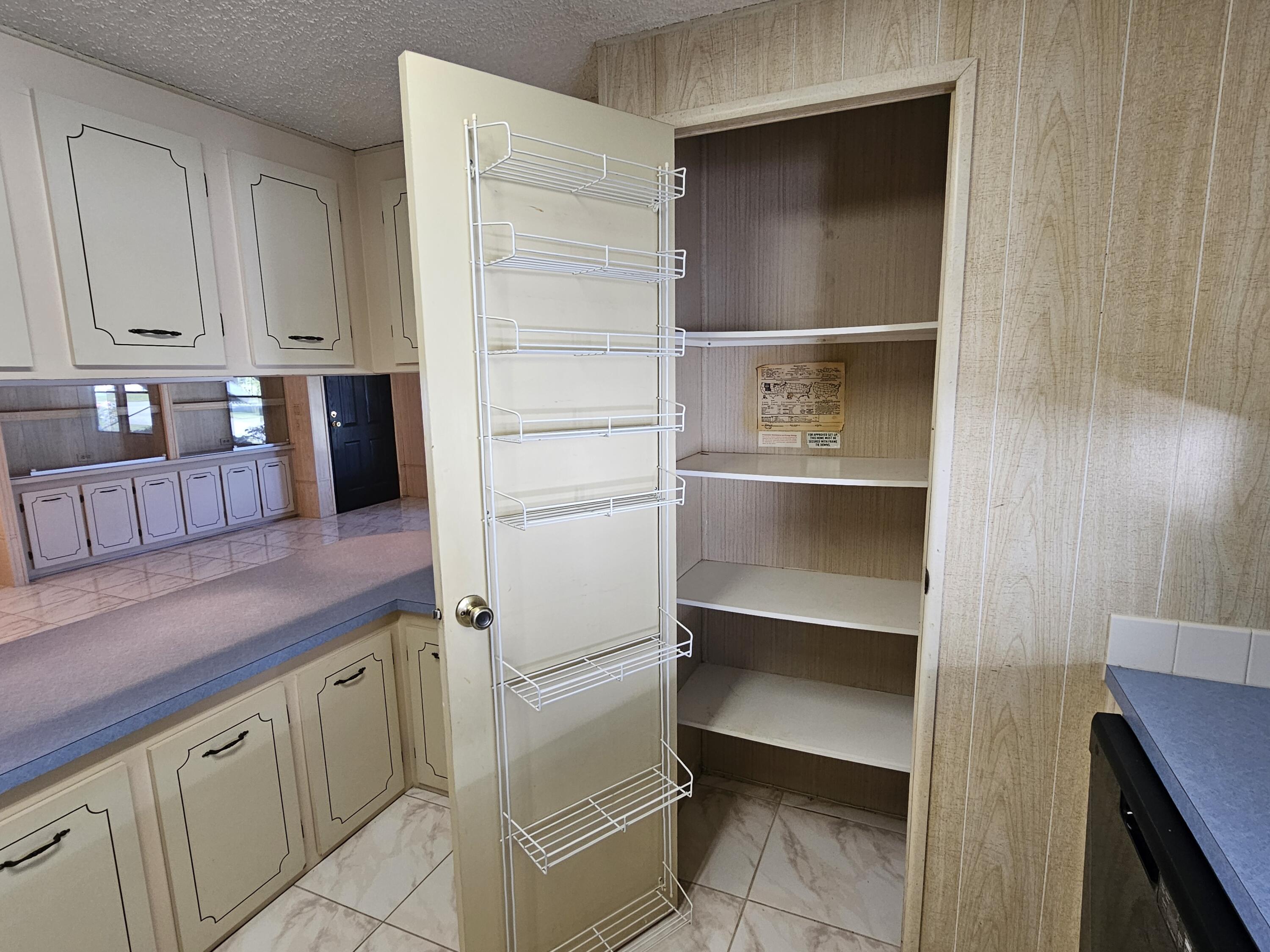 6978 Southeast Delegate Street Hobe Sound, FL 33455 - Photo 13 of 24 a kitchen with white cabinets and appliances