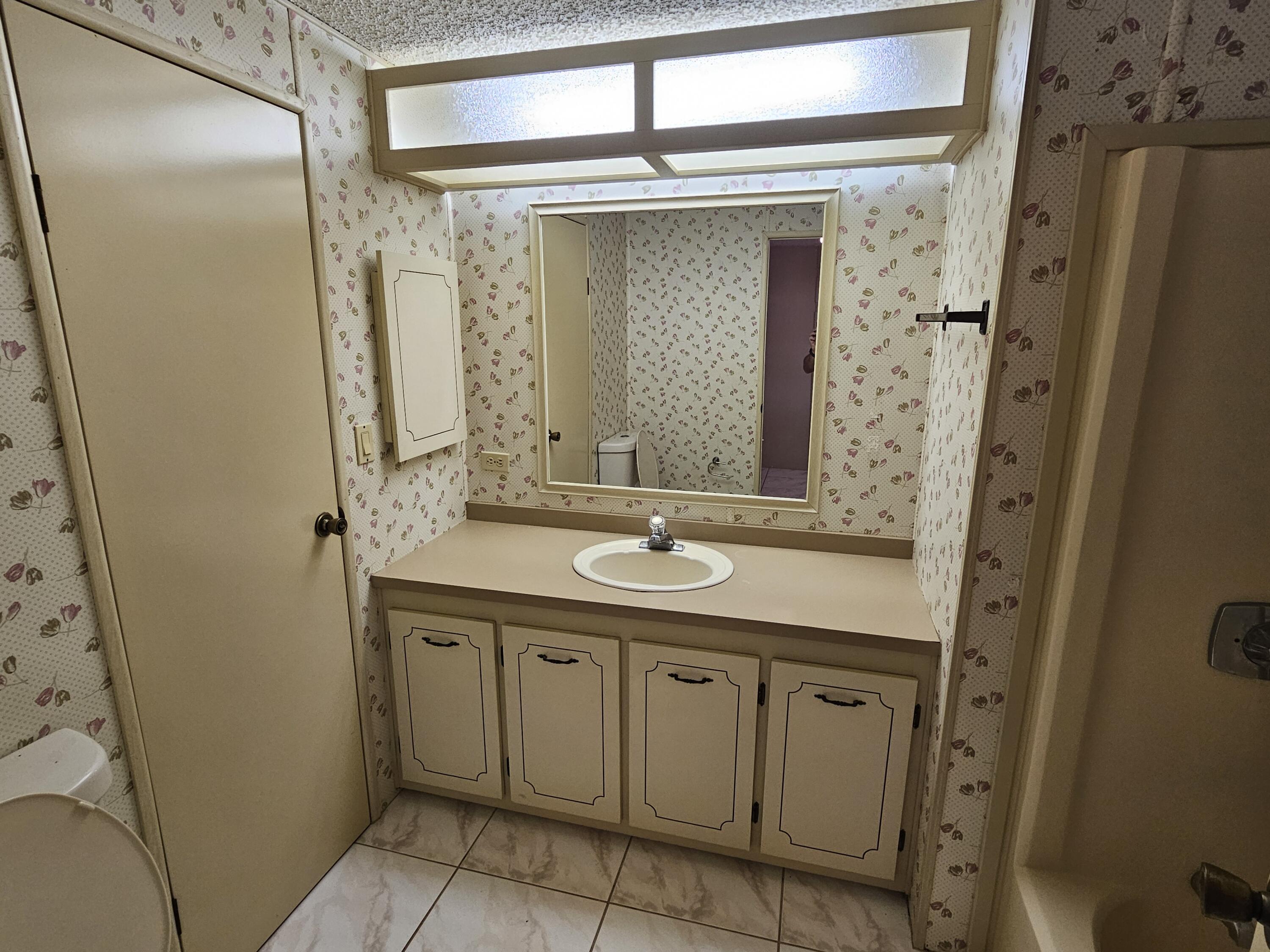 6978 Southeast Delegate Street Hobe Sound, FL 33455 - Photo 16 of 24 a bathroom with a granite countertop sink a mirror and a shower