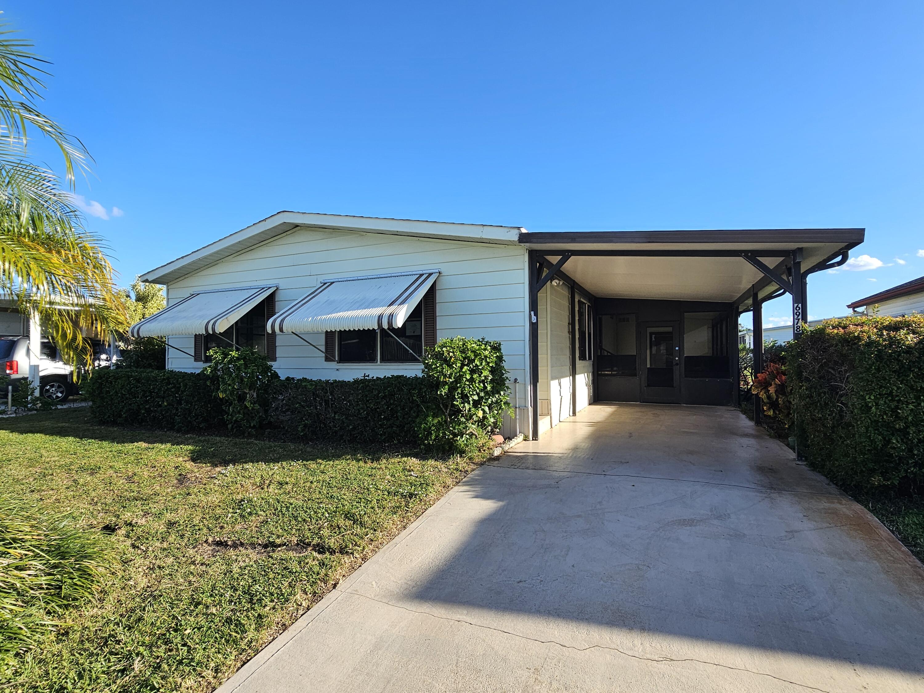 6978 Southeast Delegate Street Hobe Sound, FL 33455 - Photo 2 of 24 a view of a house with a small yard