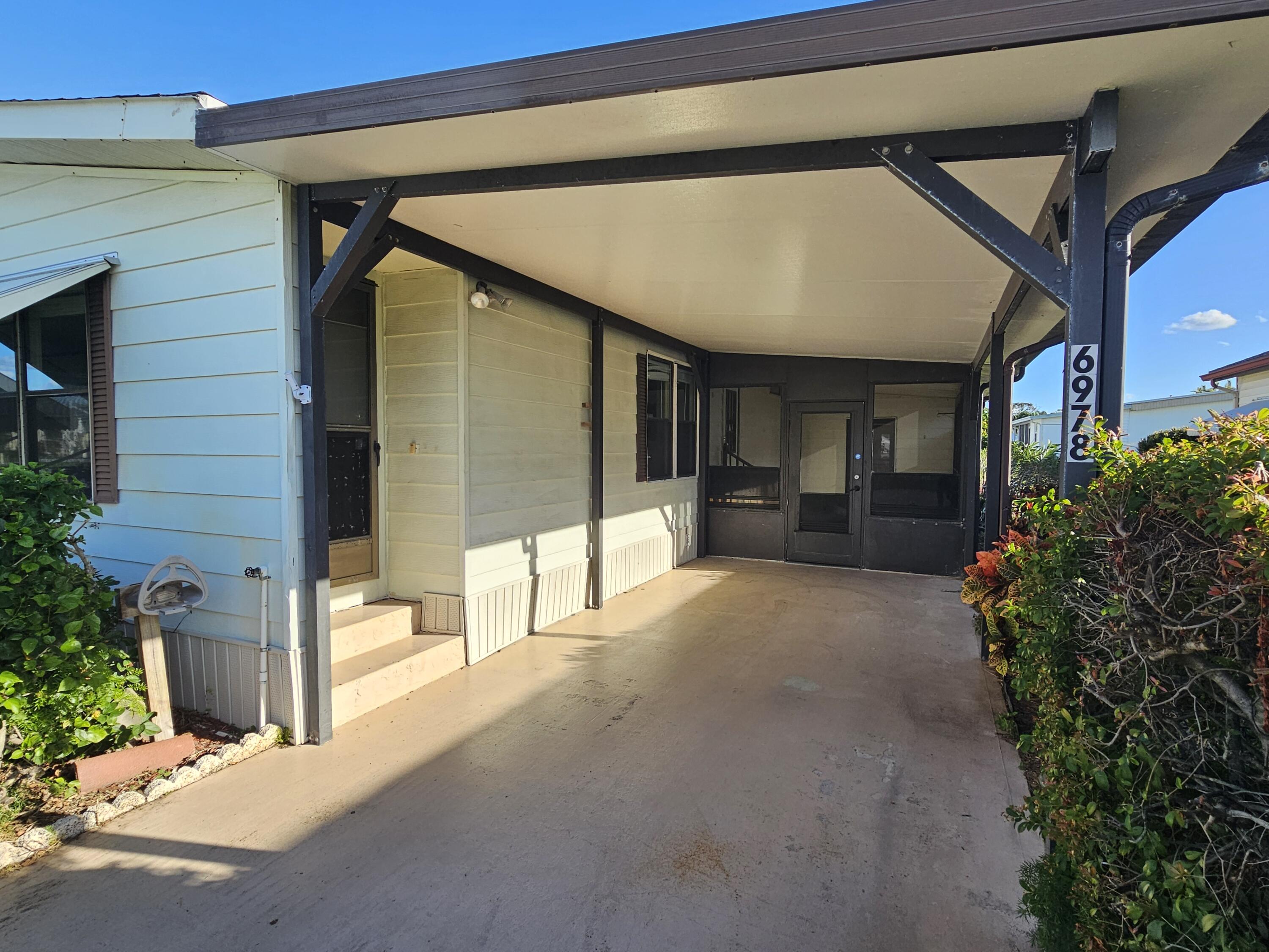 6978 Southeast Delegate Street Hobe Sound, FL 33455 - Photo 3 of 24 a view of a patio with table and chairs and potted plants