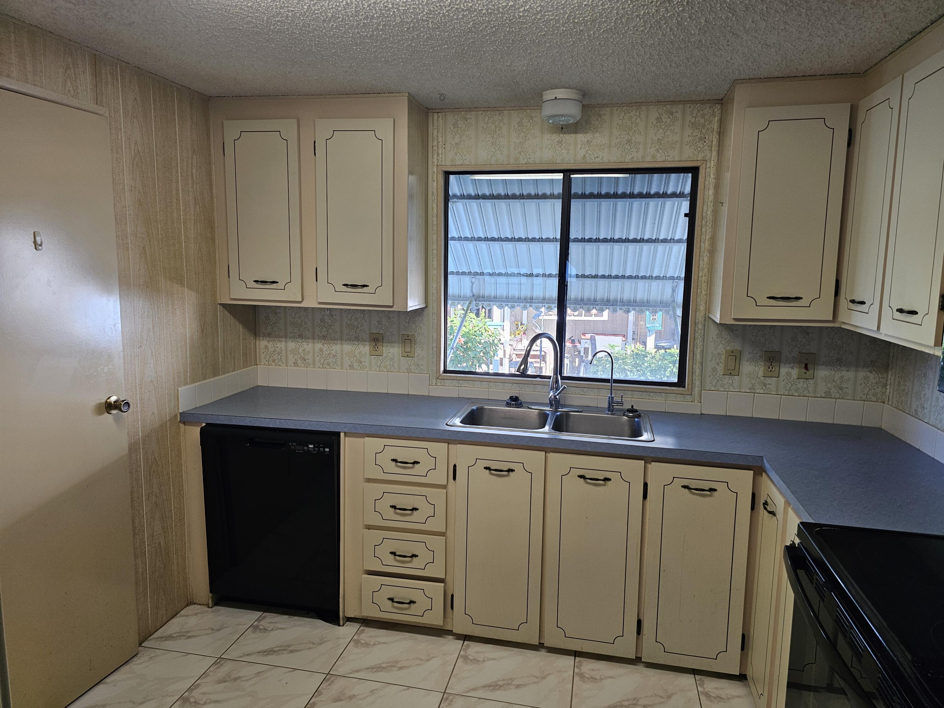 6978 Southeast Delegate Street Hobe Sound, FL 33455 - Photo 9 of 24 a kitchen with a sink window and cabinets