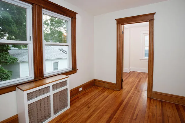 a view of an empty room with window and wooden floor