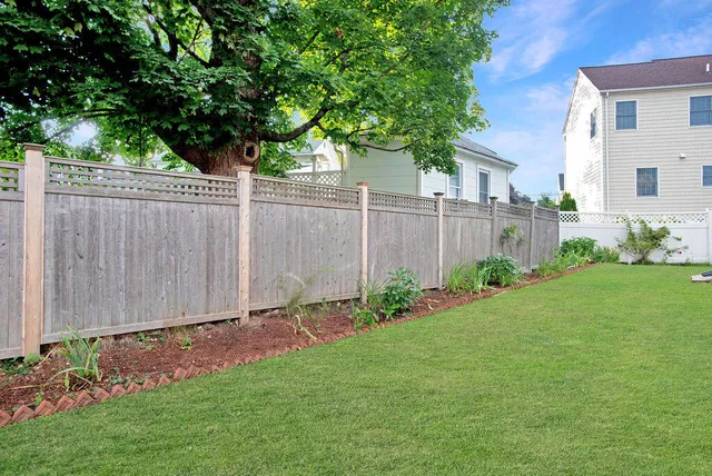 a view of a white house with large windows and plants