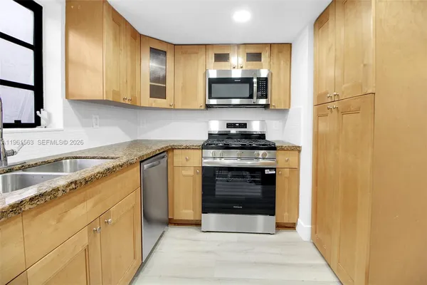 a kitchen with stainless steel appliances granite countertop a stove microwave and sink