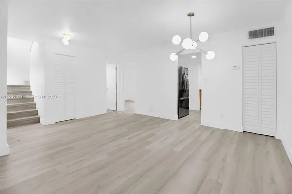 a view of an empty room with wooden floor and a ceiling fan