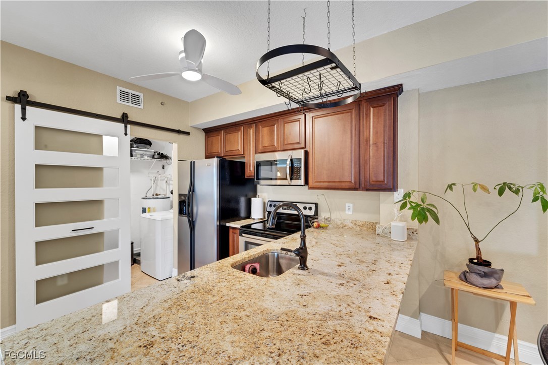 6450 Aragon Way, Unit 202 Fort Myers, FL 33966 - Photo 16 of 24 a kitchen with stainless steel appliances kitchen island granite countertop a refrigerator and a stove top oven