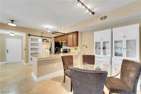 a living room with stainless steel appliances furniture a fireplace and a open kitchen view