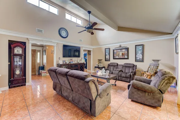 a living room with furniture a clock and a ceiling fan