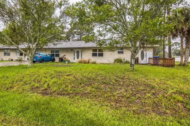 a front view of a house with a garden and trees