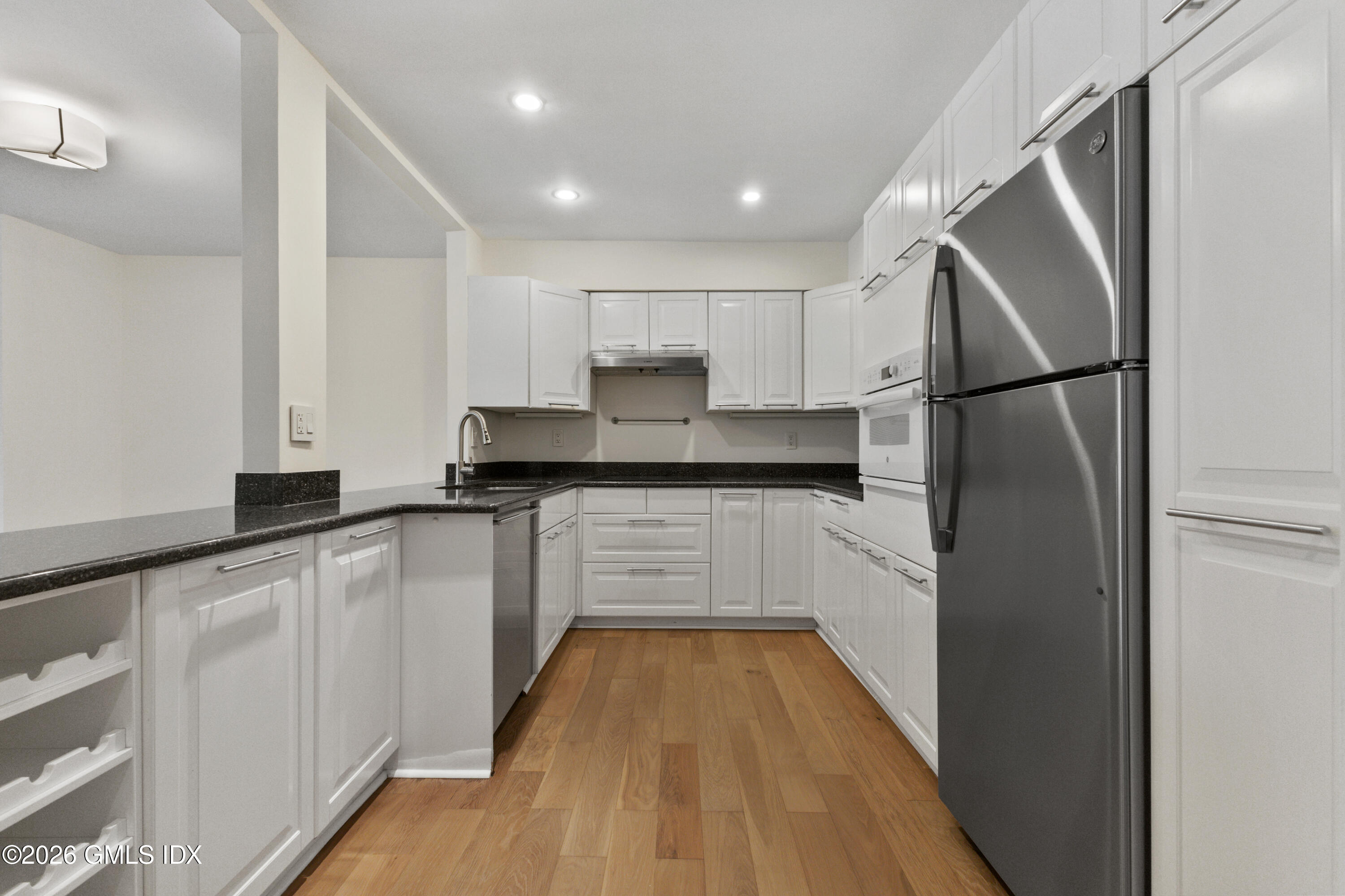 15 River Road, Unit 210 Cos Cob, CT 06807 - Photo 8 of 23 a kitchen with white cabinets and stainless steel appliances