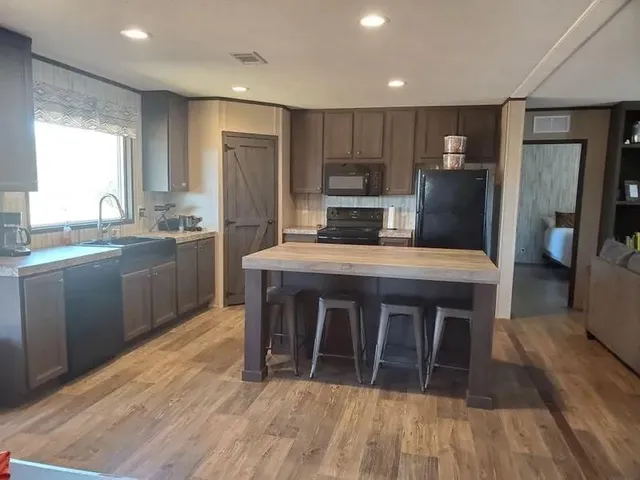 a kitchen with stainless steel appliances a stove a sink dishwasher a refrigerator cabinets and wooden floor