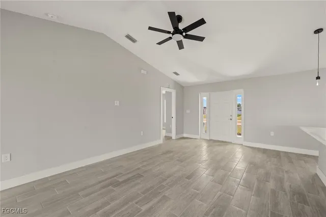 an empty room with wooden floor and ceiling fan