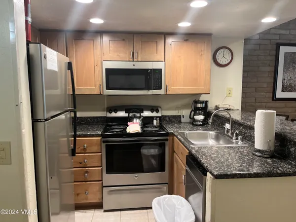 a kitchen with granite countertop a sink stove and refrigerator