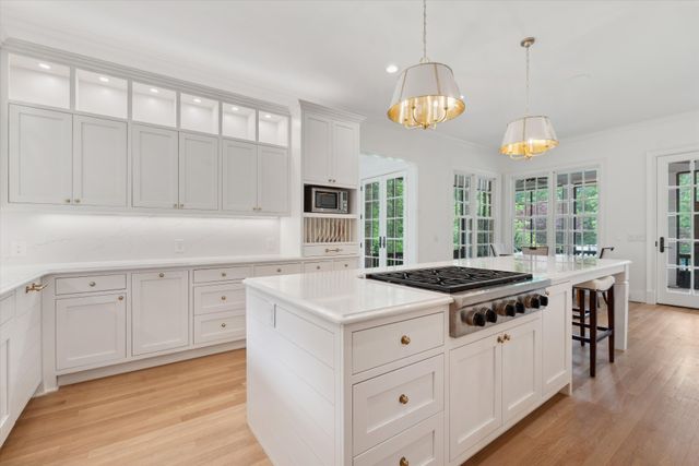 a kitchen with kitchen island granite countertop a stove a oven a dining table and chairs with wooden floor