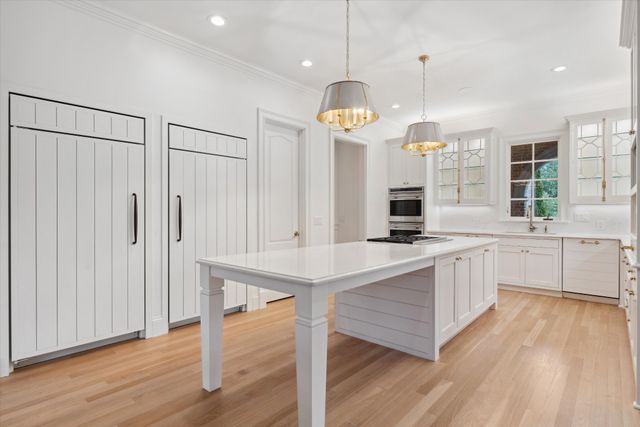 a large kitchen with a center island wooden floor stainless steel appliances and windows