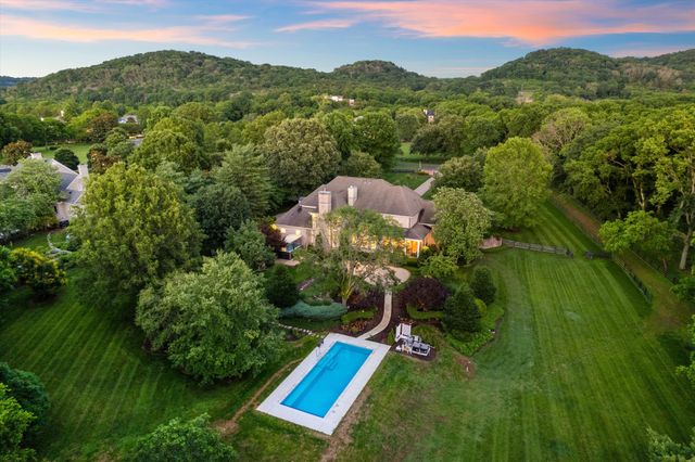 an aerial view of a house with a yard and large trees