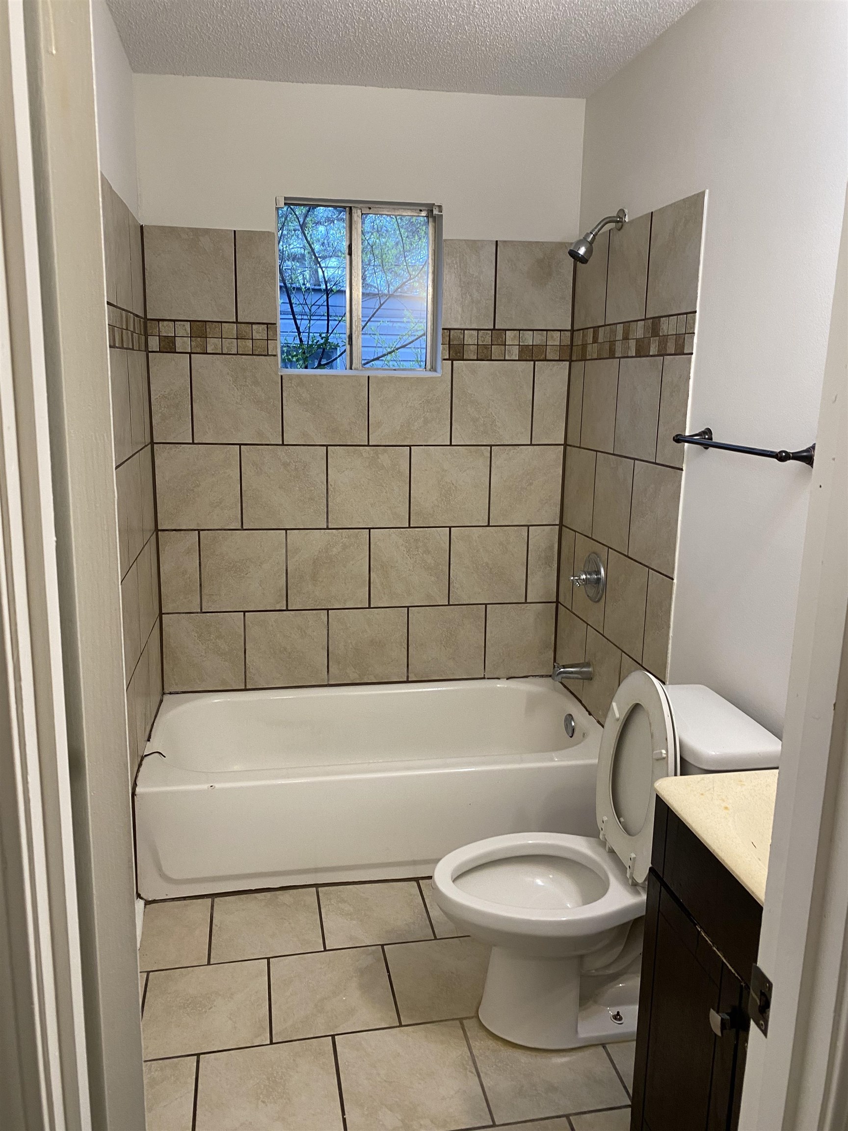 Full bath featuring vanity, bathing tub / shower combination, a textured ceiling, and light tile patterned floors.  The home offers 2 full bathrooms.