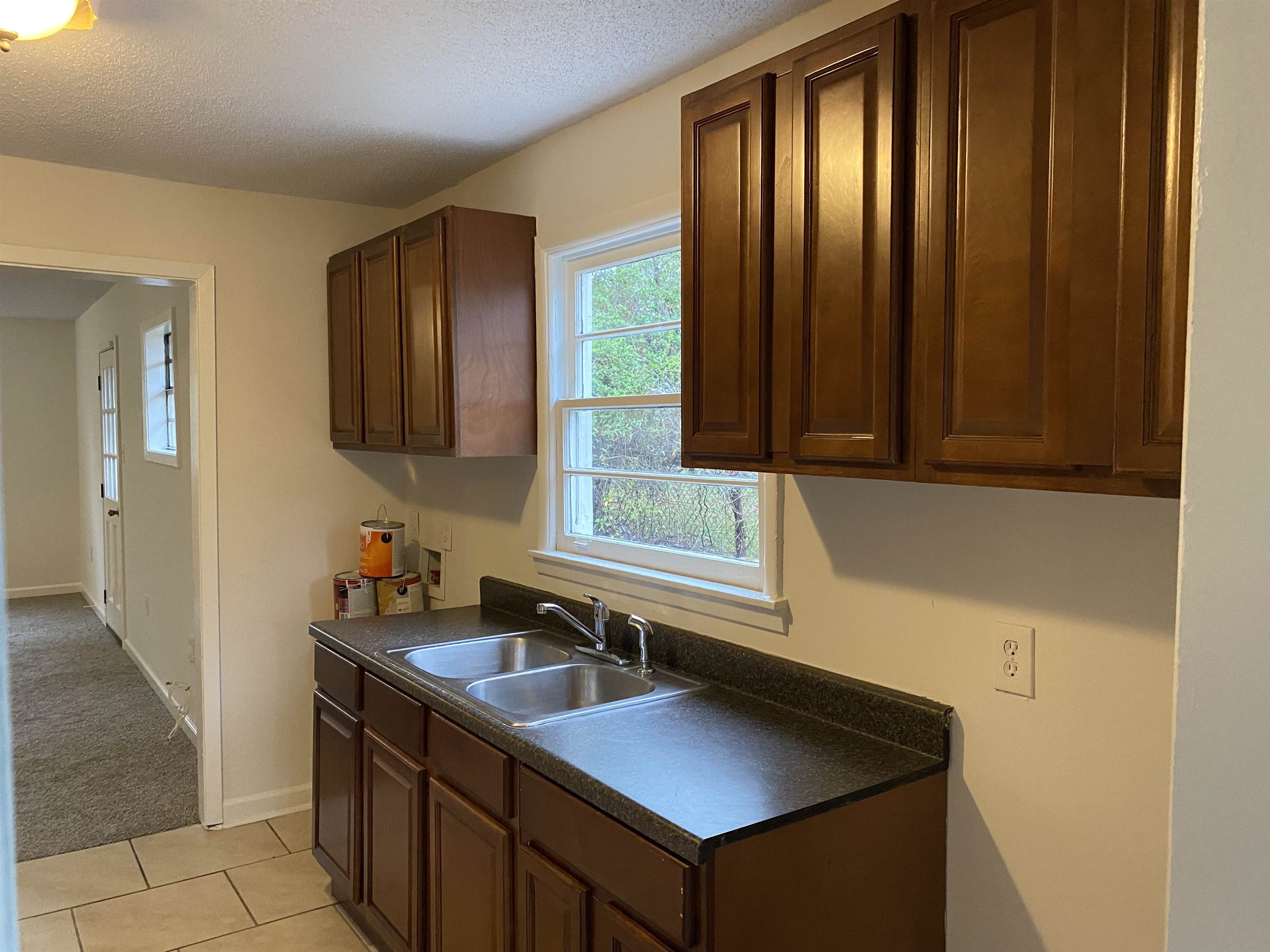 3499 Rochester Road Memphis, TN 38109 - Photo 9 of 13 Kitchen with dark countertops, a textured ceiling, light tile patterned floors, and light carpet