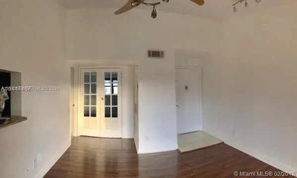 a view of a big room with wooden floor and windows