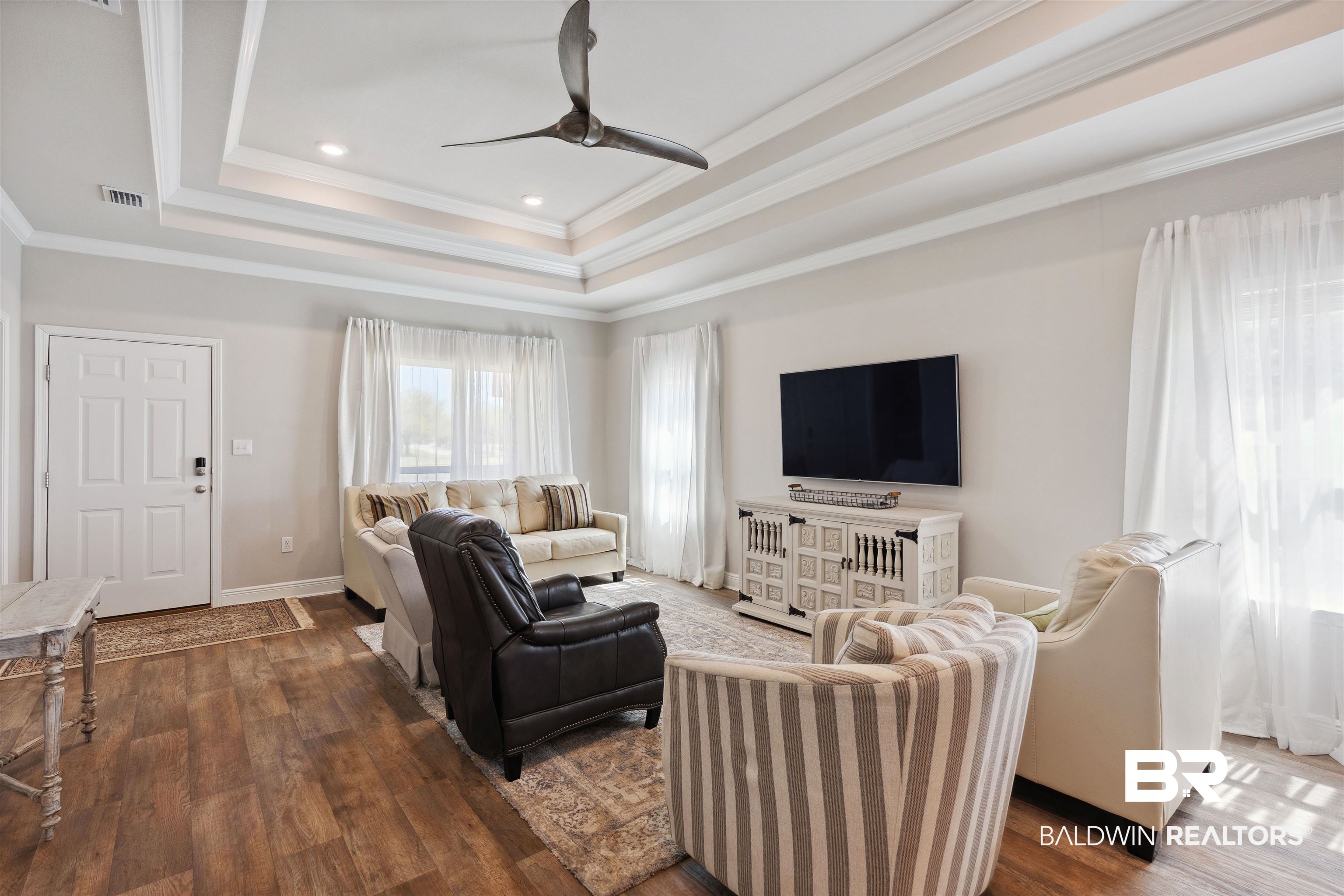 23809 Devonfield Lane Daphne, AL 36526 - Photo 2 of 29 Living area with dark wood-style floors, a tray ceiling, visible vents, and ceiling fan