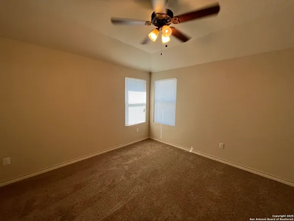 an empty room with windows and fan