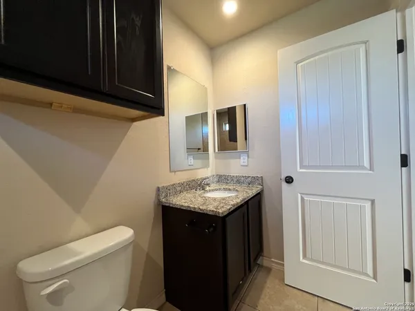 a bathroom with a granite countertop toilet sink and mirror