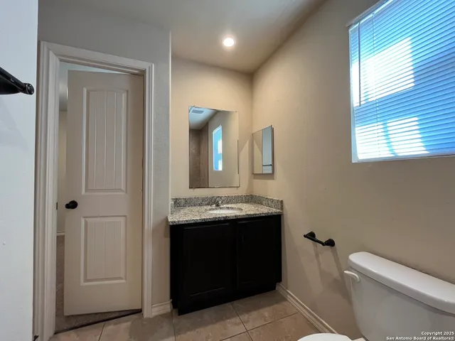 a bathroom with a granite countertop sink a toilet and a mirror