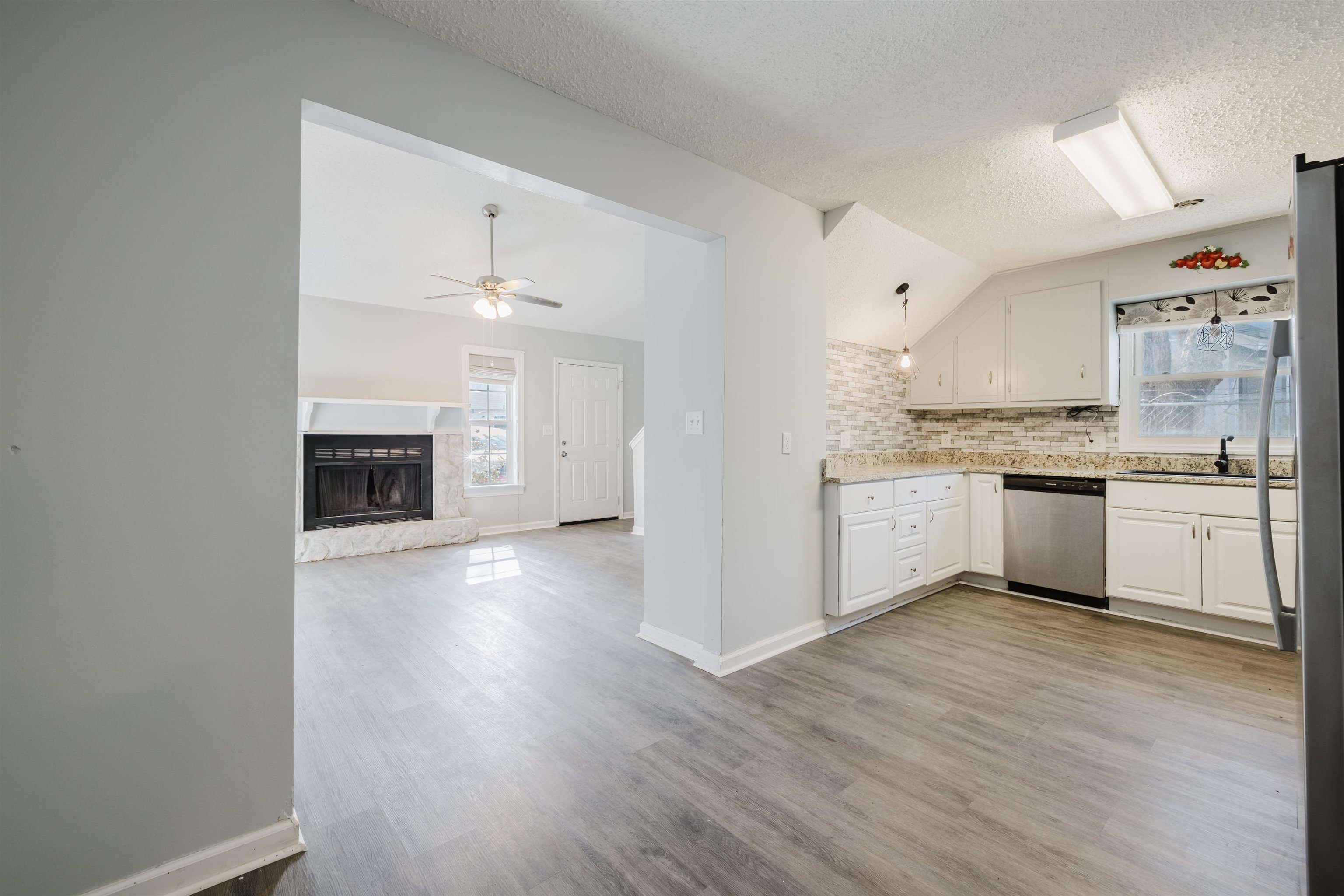 90 Freedom Way Myrtle Beach, SC 29577 - Photo 5 of 16 Kitchen featuring a premium fireplace, backsplash, white cabinets, stainless steel appliances, and wood finished floors