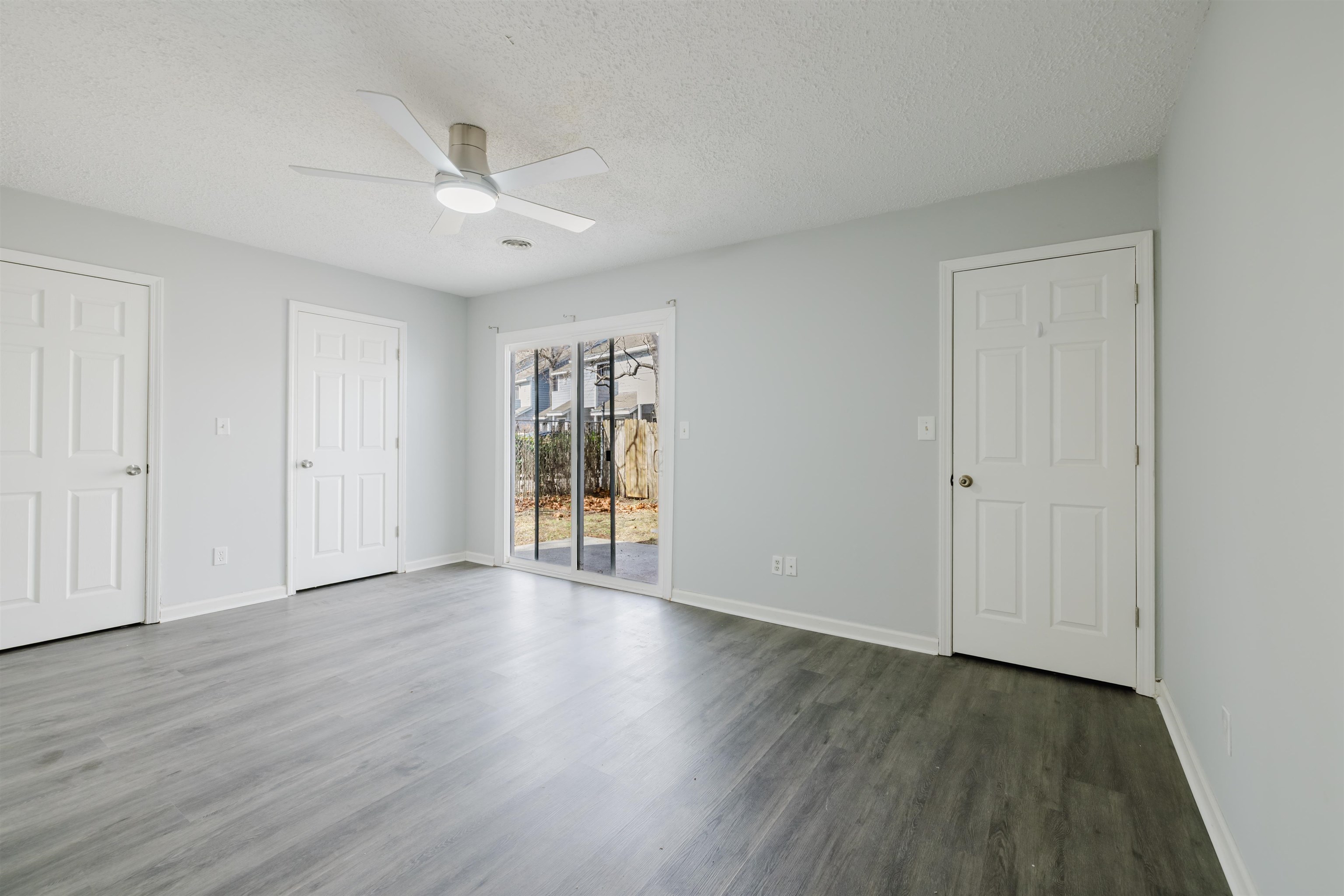 90 Freedom Way Myrtle Beach, SC 29577 - Photo 8 of 16 Unfurnished bedroom featuring access to outside, a textured ceiling, ceiling fan, dark wood-type flooring, and two closets