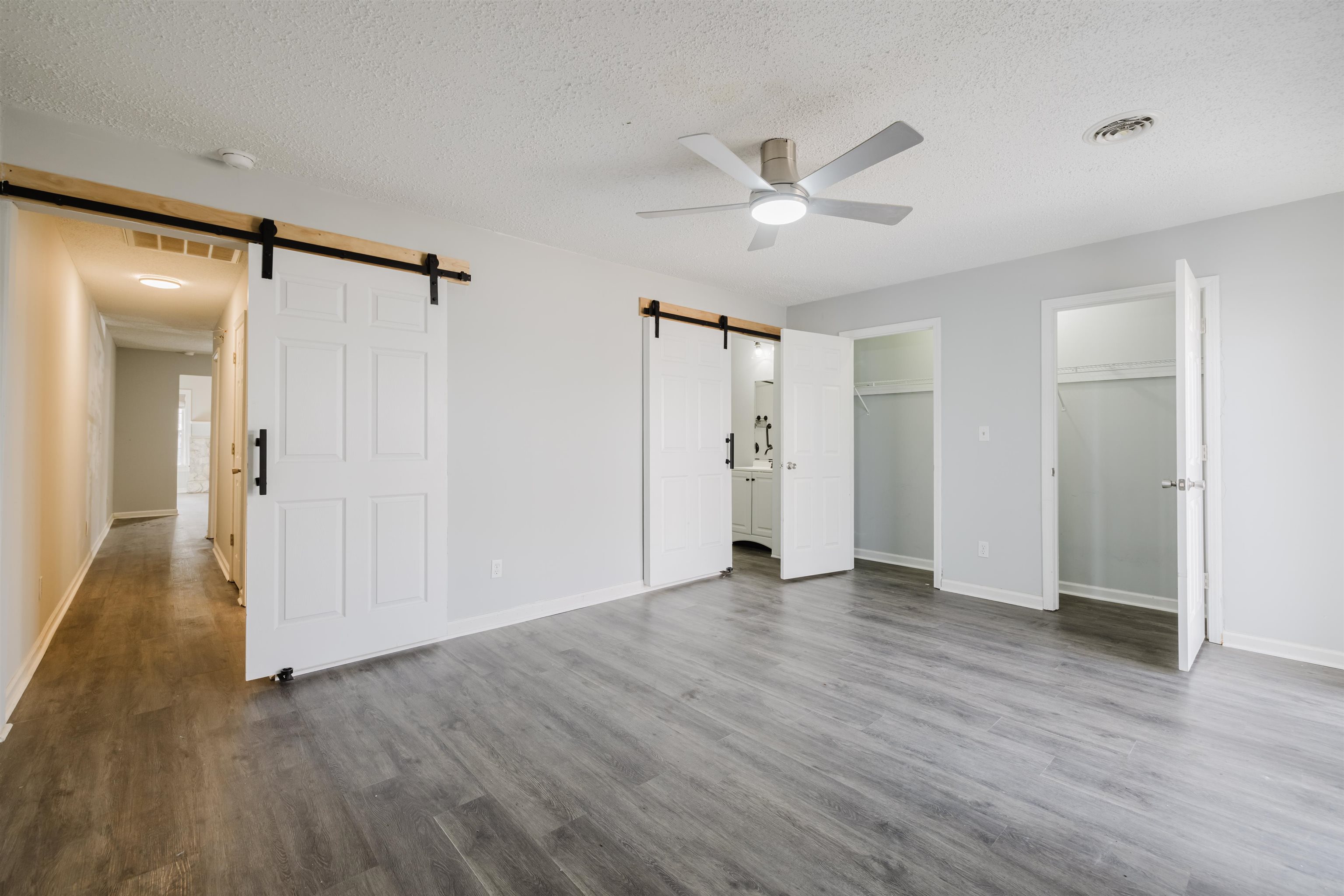 90 Freedom Way Myrtle Beach, SC 29577 - Photo 9 of 16 Unfurnished bedroom with two closets, a barn door, wood finished floors, a textured ceiling, and ceiling fan